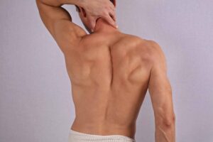 Muscular man undergoing hair removal on his back, torso, chest, and armpits, highlighting male waxing and laser back hair removal treatments